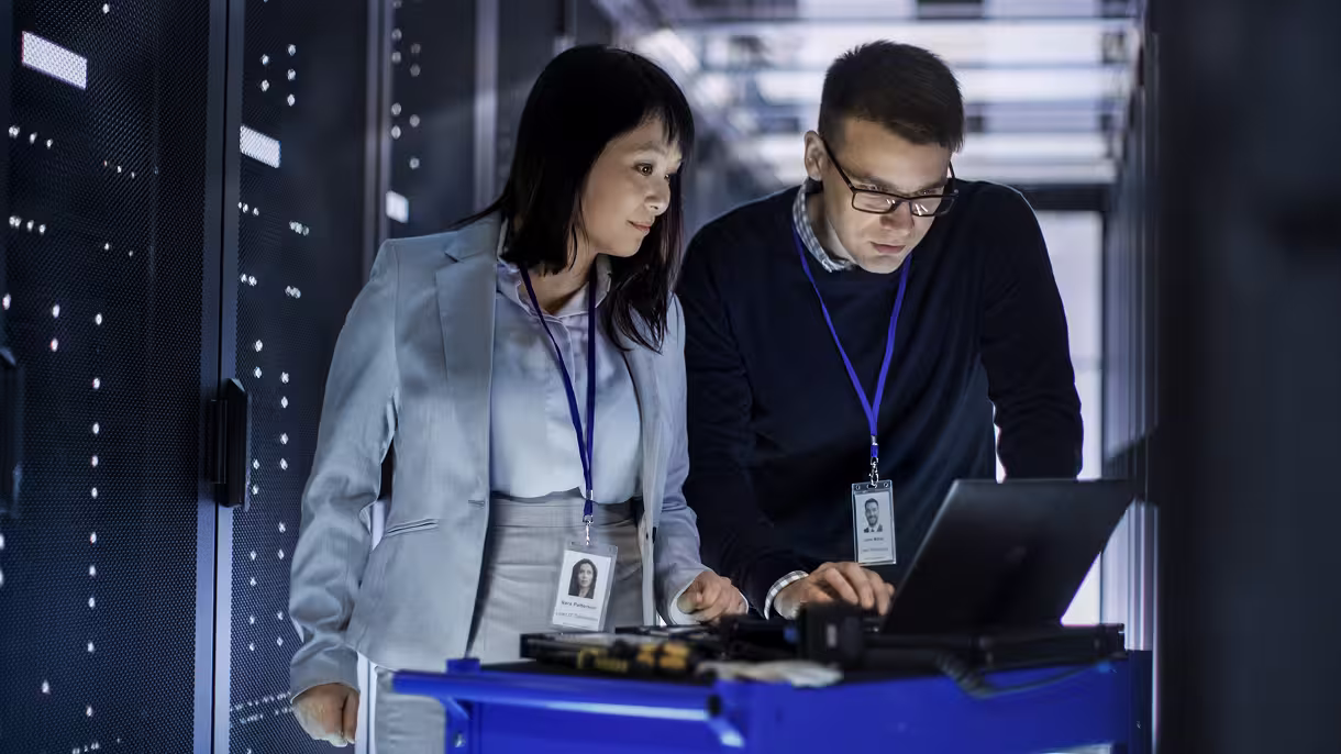 Two colleagues looking at a laptop screen.